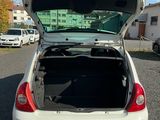 une voiture blanche dont le coffre est ouvert, garée sur un parking