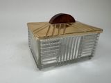 une boîte en verre avec un couvercle en bois posée sur une surface blanche