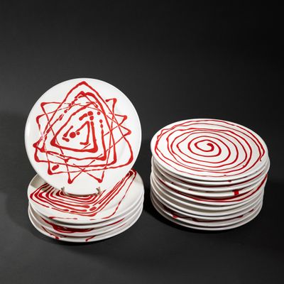 several white plates with red designs are stacked on top of each other