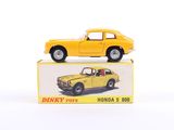 yellow toy car sitting on top of a box on a white surface