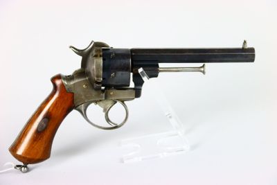 un vieux revolver avec une poignée en bois sur une surface blanche