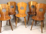 quatre chaises en bois sont alignées contre un mur gris