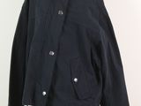 La veste est posée sur un support de mannequin, avec un mur blanc en arrière-plan.