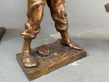 bronze statue of a man holding a baseball bat on a base