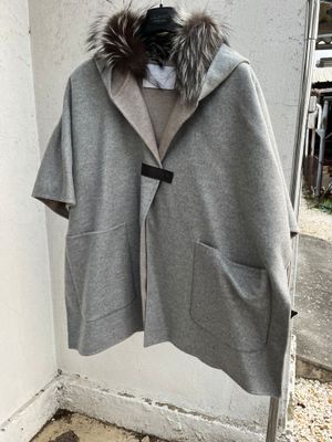 grey coat with fur collar and hood hanging on a wall