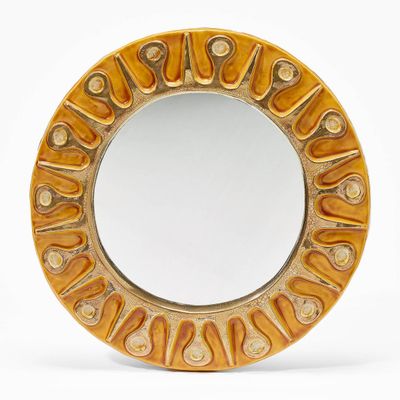 a round mirror that has a design on it
