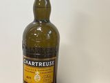 une photo d'une bouteille de whisky Chartreuse posée sur une table en bois