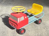 a red toy truck with a yellow seat and steering wheel