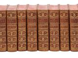 six vieux livres sont alignés en rangées sur une surface blanche