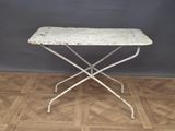 an old white iron table with a wooden top on a parquet floor