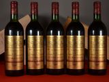 four bottles of wine are lined up on a red table