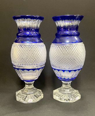 une paire de vases en verre bleu posés sur une table, sur fond gris