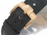 a black strap with a gold buckle on a watch