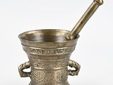 un mortier et un pilon anciens en laiton sur fond blanc