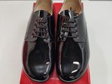 une paire de chaussures noires posée sur une boîte rouge, elle-même posée sur une surface blanche