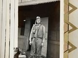 a black and white photo of a man standing in front of a house