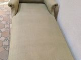 a chaise lounger with a plant in the corner of the room