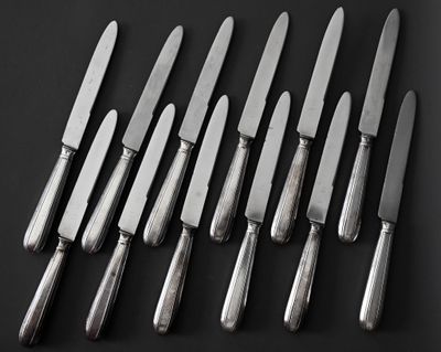 six couteaux sont alignés les uns à côté des autres sur une surface noire
