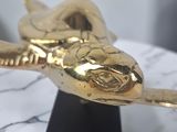 a gold statue of a snake on a marble table