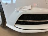 the front of a white car with a measuring tape on it ' s bumper