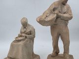 deux sculptures en argile représentant un homme et une femme assis sur un banc