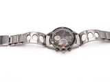 un gros plan d'une montre montée sur un bracelet en métal, posée sur une surface blanche