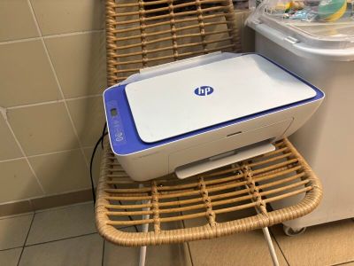 a printer sitting on a wicker chair next to a washing machine