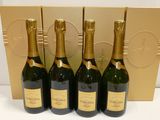 quatre bouteilles de champagne sont alignées devant un coffret doré
