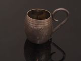 a silver cup with a handle on a black surface