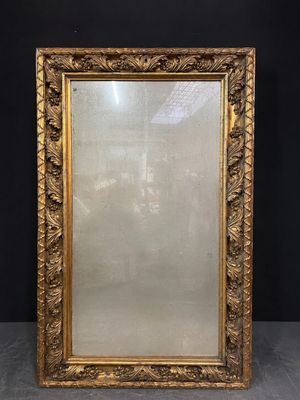 un miroir à cadre doré posé sur une table près d'un mur noir
