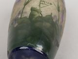 a glass vase with purple flowers on it on a white surface
