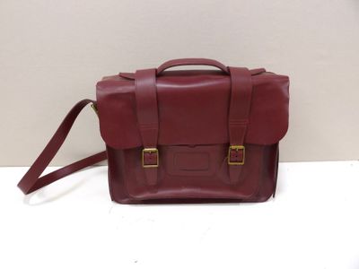 a close up of a red leather bag on a white surface