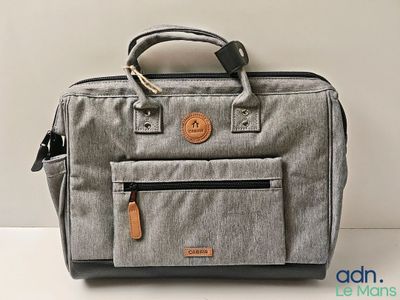an image of a grey bag with a leather handle on a white surface