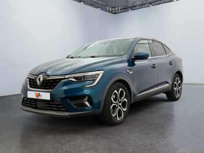 Une voiture bleue est garée dans une grande pièce aux murs blancs.
