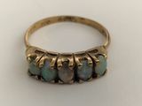a close up of a gold ring with five oplite stones
