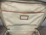a white suitcase with a brown handle sitting on the floor