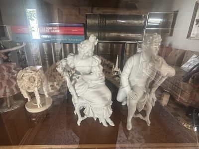 statues of people sitting on a bench in a glass case