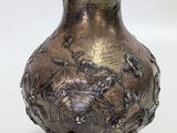 a silver vase that is sitting on a white surface
