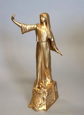 statue en or représentant une femme tenant un oiseau, posée sur un socle