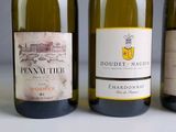 three bottles of white wine are lined up on a table