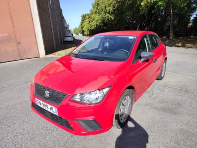 La voiture rouge est garée sur le parking, à côté d'un immeuble.