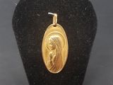 a gold plated pendant with a woman ' s face on it