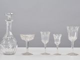 five wine glasses and a decanter sitting on a table