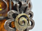 a close up of a metal vase with a flower on it