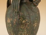 un grand vase vert avec un oiseau sur l'anse