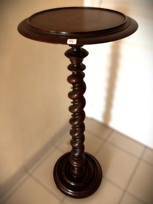 a wooden table with a round top on a tile floor