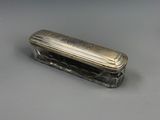 une vieille boîte en argent avec un couvercle, posée sur une surface grise