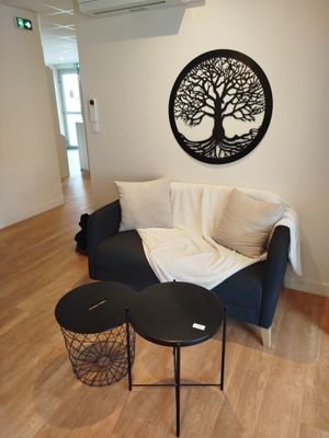un salon avec un canapé, une table et un arbre accroché au mur