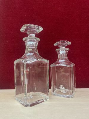 two glass bottles sitting on a table with a red background