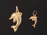 a pair of gold dolphin pendants on a black background